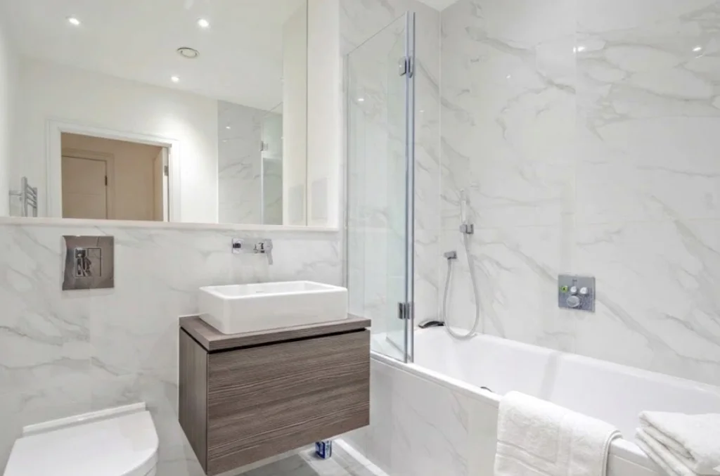 Family bathroom with bath, shower over and marble tiling at The Avenue, Queen's Park NW6